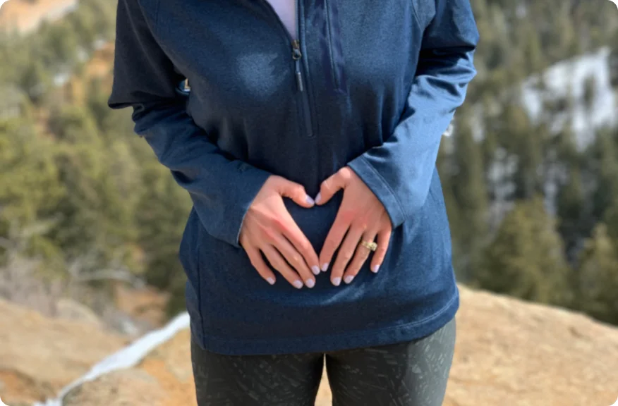 Mujer de pie con las manos sobre el estómago, representando la posibilidad de encuentros íntimos significativos y satisfactorios después de la cirugía de ostomía.